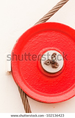 The red fairlead pulley has a grooved rim and is used as a guide around which the cable can pass in order to change direction of the pull on the load