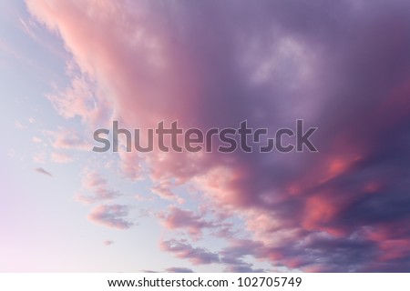 Background of a soft diffused colourful sunset in shades of pink, purple and lilac in a cloudy sky
