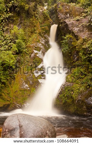 Forest waterfall cascading down rocky slope with silky appearance from long exposure