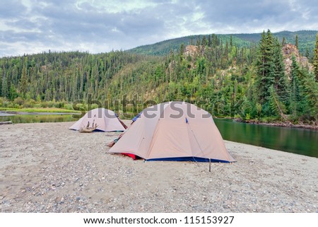 Two tents pitched on a sand bar alongside McQuesten River, Yukon Territory, Canada, in remote boreal forest wilderness