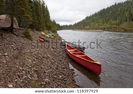 Tent camp in boreal forest and canoes on paddle river trip on McQuesten River, Yukon Territory, Canada