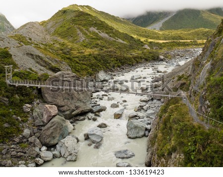 Simple suspension swing bridge crossing a rocky mountain river in Aoraki/ Mount Cook National Park  South Island  New Zealand