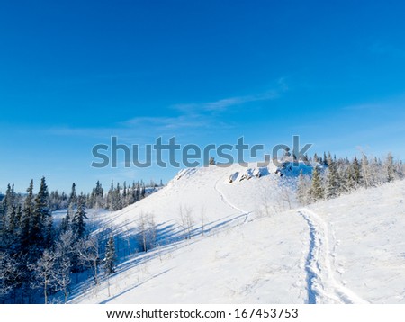 Snow-shoe trail prints in deep powder snow on hills in pristine winter wonderland wilderness