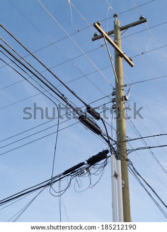 Utility pole hung with confusing and messed-up electricity power cables and telephone lines for residential supply