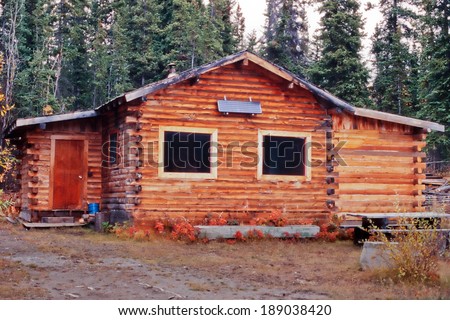 Old weathered traditional Yukon log cabin with exterior off-grid solar panel in the boreal forest taiga of Yukon Territory, Canada