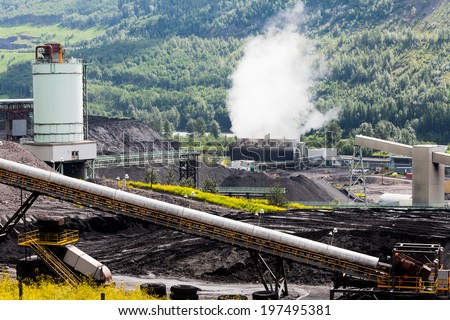 Black coal mine pile at coal fired electrical energy power station in green valley contributes to global warming