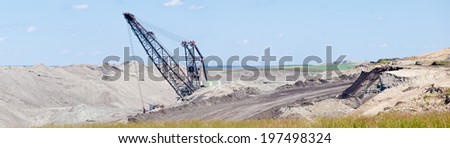 Coal mine industrial excavator machinery equipment among moon-like tailings landscape panorama in Alberta, Canada