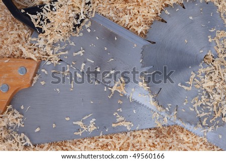 Background with softwood shavings and steel of circular saw blade and two handsaws all with sharp teeth.