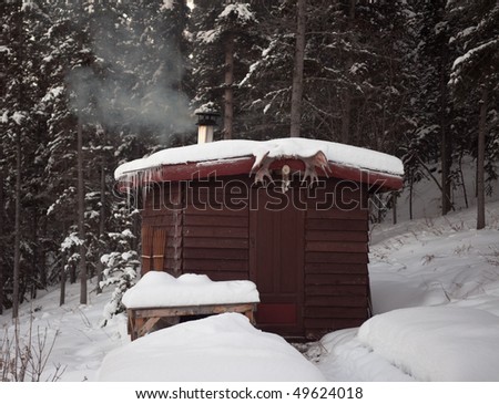 Smoking wood stove is heating up small sauna hut in winterly boreal forest
