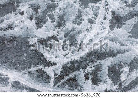 Surface of thick ice layer on lake, weathered by numerous thaw and freeze cycles.