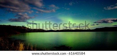 Intense Aurora borealis (northern lights) in moon lit night being mirrored on Lake Laberge, Yukon Territory, Canada.
