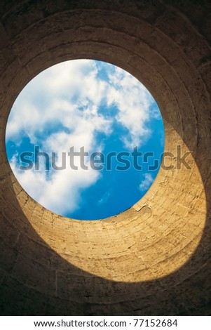 Looking up from the interior of a cooling tower/ chimney showing a blue-white circle of sky resembling our blue planet earth in space.