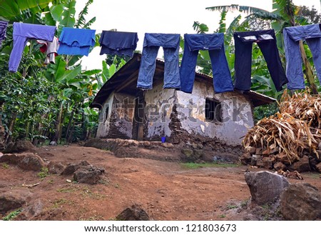 Laundry on a washing lines with mud brick house in a poor area with banana plantation in the background