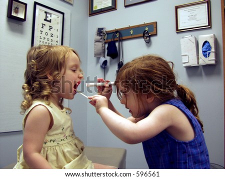 Two little girls playing in a medical office with one girl checking the other one\'s throat