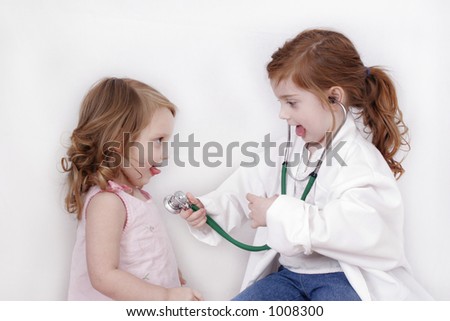 Little girl with stethoscope listening to her sister\'s heart