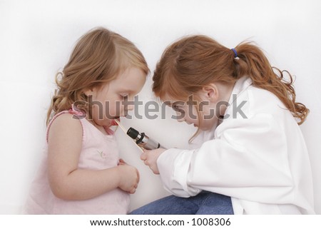 Two little girls playing doctor with a white background.