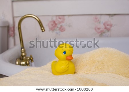 Rubber ducky resting on a towel by bathtub