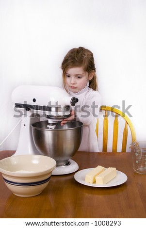 Cute little girl using a mixer to mix up a batch of cookies.