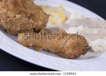 Close-up of a homestyle dinner with chicken, mashed potatoes and gravy, creamed corn and baking powder biscuit.