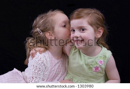 Little sister giving big sister a big kiss.