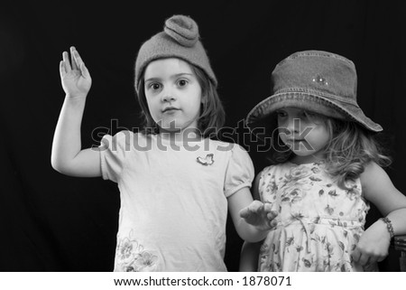 Unusual portrait of little girls in hats playing together.