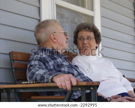 Elderly man and woman sitting on their front porch.