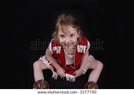 Cute little smiling girl in a cowgirl outfit.