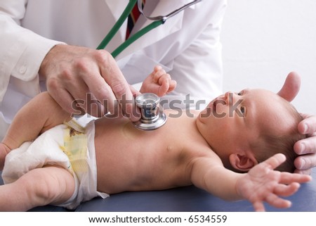 Doctor using a stethoscope to listen to a newborn baby\'s heart.