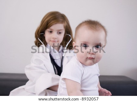 Little girl playing doctor with a baby (high-key).