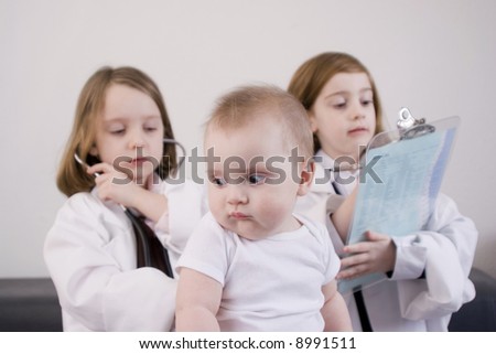 Three little girls playing doctor in a doctor\'s office.