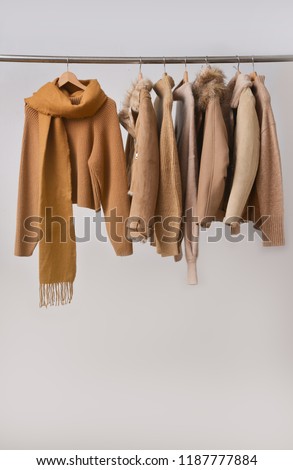 Women coat and fur jacket with sweater with scarf on hangers isolated