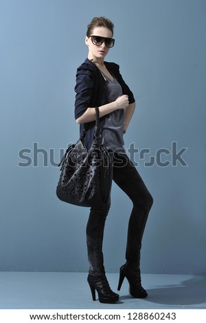 Full body young stylish slim woman in sunglasses holding bag