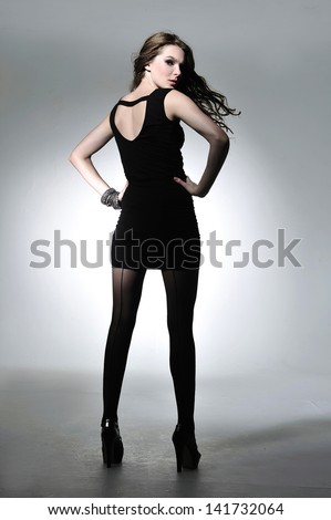 Full body sexy woman in black dress back on light background