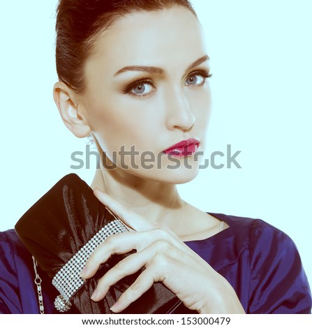Portrait of face of brunette woman with fashion makeup and red lips holding purse Ã¢Â?Â?light blue background