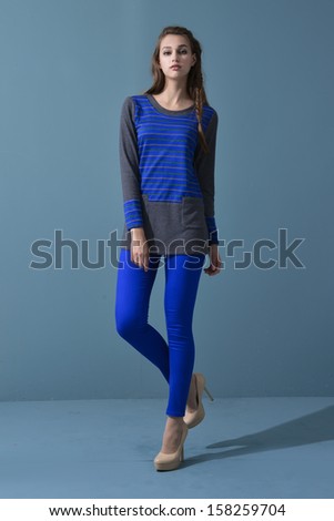 full body fashion model standing against on blue background