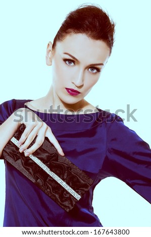 Portrait of face of brunette woman with fashion makeup and red lips holding purse