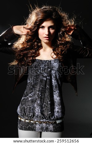 Young brunette lady in black dress posing-black background