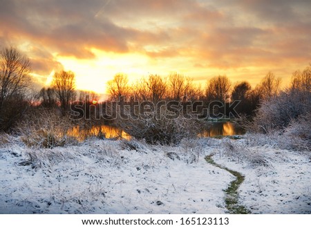 Winter landscape with sun and frozen river. Sunrise.