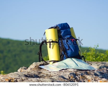 Backpack and map in mountain.nature composition.