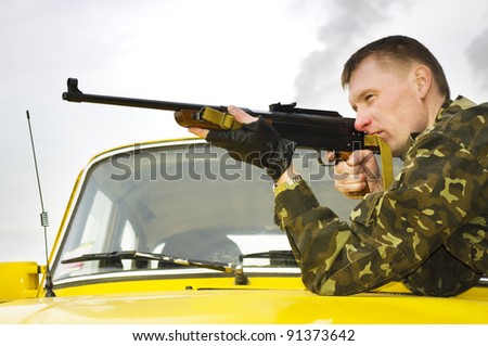Sniper in camouflage on car at sunset outdoor.