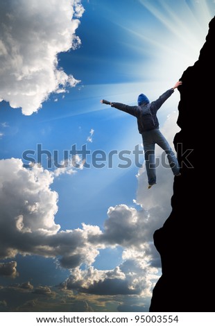 rock climber climbs the steep cliff to the top against the blue sky