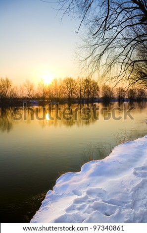 Sunset over frozen river in winter,