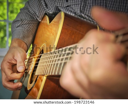 Image of a man playing an acoustic guitar.