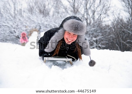 laughing girl in winter clothing goes down on sleds down the hill