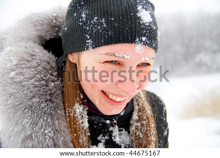 laughing girl with snow on her face staying in a winter woods