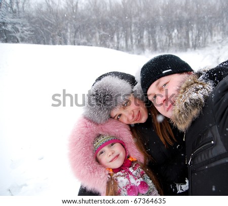 father, mother and their daughter in winter clothing in a winter woods