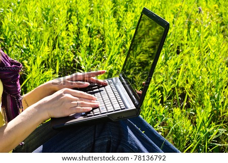 Hands of young woman on laptop outdoor. Sunny summer day.