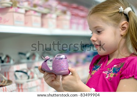 A little girl in a shoe store holding shoe