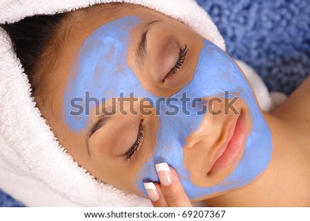 Young female relaxes while receiving a blue spa facial.