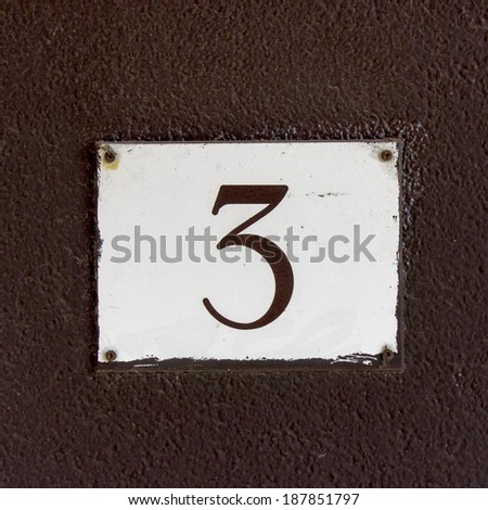 house number three. Brown lettering on a white plastic plate
